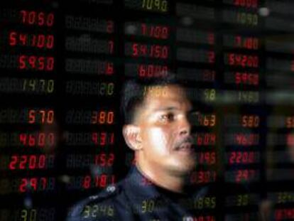 Un hombre reflejado en una pantalla que muetra la evolución de varios valores burstátiles en la compañía de compraventa de acciones en Yakarta (Indonesia). EFE/Archivo