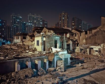 Postal nocturna de un suburbio en Shanghai, con edicifios semiderruidos en primer plano, que han quedado de forma temporal en pie mientras se preparada el terreno para la construcción de nuevos rascacielos.