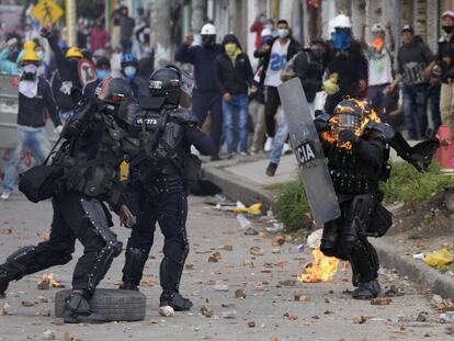 Varios policías corren para auxiliar a un compañero que fue alcanzado con una bomba de gasolina durante una protesta contra el gobierno de Iván Duque, en junio de 2021.