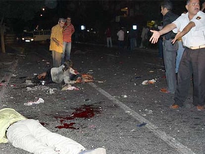 Un policía gesticula ante de un cadáver mientras una mujer herida espera ayuda anoche en Diyarbakir.