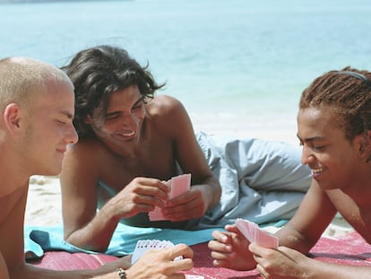 Un grupo de chicos en la playa jugando a las cartas.