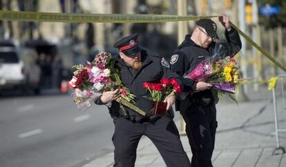 Policías ponen flores donde fue asesinado el soldado canadiense.