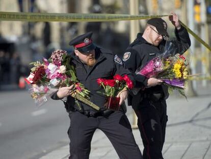 Policías ponen flores donde fue asesinado el soldado canadiense.