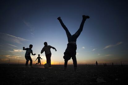 Niños sirios juegan al fútbol, mientras otro hace el pino en el campo de refugiados de Zaatari, cerca de la frontera con Siria, en Jordania, 24 de octubre de 2013.