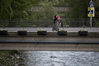 Una mujer cruza un puente sobre el río Ter en Ripoll junto a su hija.

