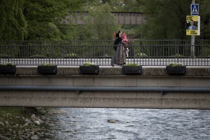 Una mujer cruza un puente sobre el río Ter en Ripoll junto a su hija.

