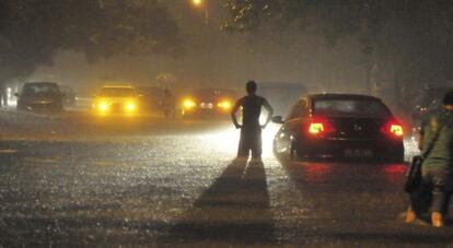 Un conductor observa la carretera inundada por las lluvias torrenciales en Pekín, el 21 de julio de 2012.