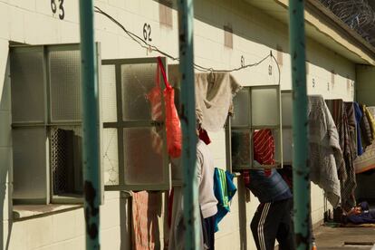 Un interno mira hacia el interior de una celda en un pabellón hacinado.