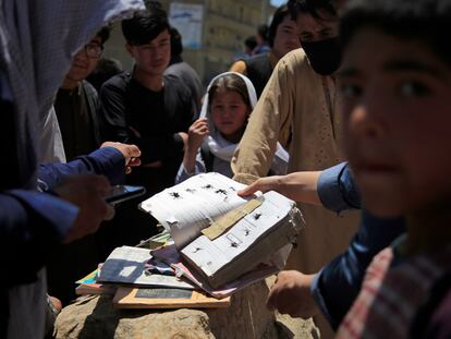 Varios afganos muestran algunas de los cuadernos y libros de las víctimas del atentado junto a un colegio de Kabul, el domingo.