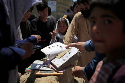 Varios afganos muestran algunas de los cuadernos y libros de las víctimas del atentado junto a un colegio de Kabul, el domingo.