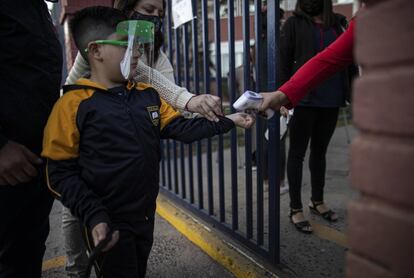 Al estudiante Román Catalán, de seis años, le toman la temperatura antes de ingresar al edificio para su primer día de clases presenciales, este marzo en Chile.