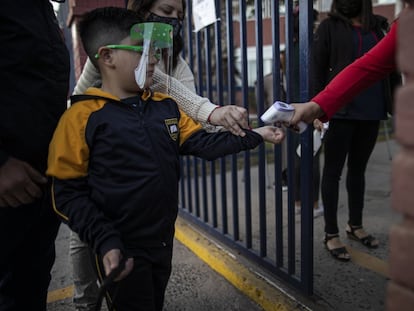 Al estudiante Román Catalán, de seis años, le toman la temperatura antes de ingresar al edificio para su primer día de clases presenciales, este marzo en Chile.