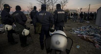 Varios policías vigilan a un grupo de refugiados en Grecia.