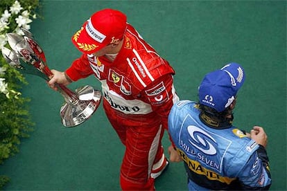 Michael Schumacher, con su trofeo, se cruza con Fernando Alonso.
