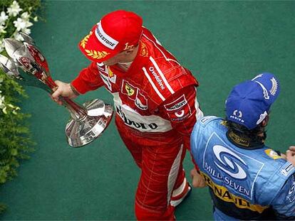 Michael Schumacher, con su trofeo, se cruza con Fernando Alonso.