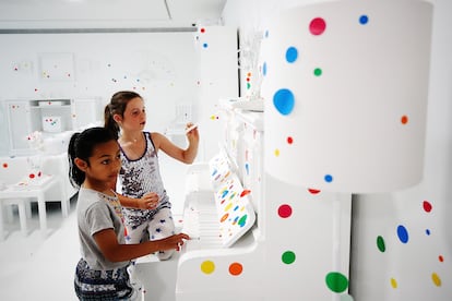 Dos niñas añaden su marca en la instalación de Yayoi Kusama ‘La habitación de la devastación’, en la galería de arte de Auckland (Nueva Zelanda) el 9 de diciembre de 2017. Las paredes, el techo, los muebles y objetos blancos en la habitación fueron progresivamente borrados por la masa creciente de puntos coloridos de distintos tamaños añadidos por los visitantes en todas las superficies.