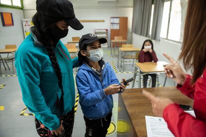 Santiago Medino, de 10 años, recibe uno de los teléfonos celulares reparados por Tiberio Malaiu para poder atender a sus clases en línea del colegio Carlos Fernández, en Santiago de Chile.