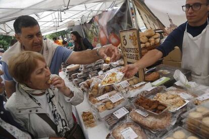 Dos transeúntes degustan pasteles en uno de los puestos del comercio gastronómico vasco.