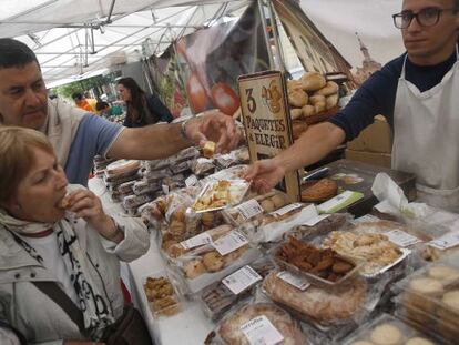 Dos transeúntes degustan pasteles en uno de los puestos del comercio gastronómico vasco.