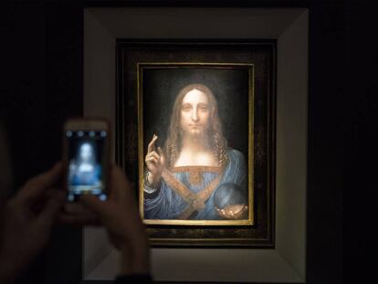 Un visitante toma una foto del Salvador Mundi en Christie&#039;s.