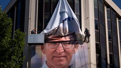 Operarios retiran el pasado lunes el cartel de Alberto Núñez Feijóo, candidato a la presidencia del Gobierno, de la fachada del Partido Popular en Madrid.
