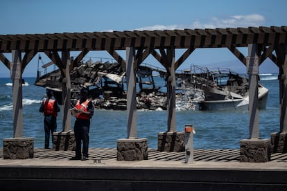 Guardacostas en el puerto de Lahaina ante un barco calcinado, este viernes en la isla de Maui (Hawái).