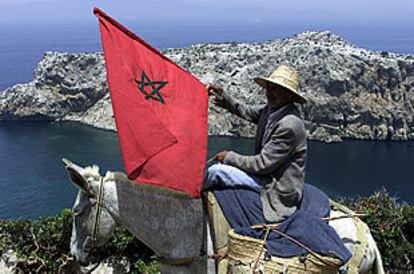 Un marroquí enarbola una bandera de su país frente al islote de Perejil.