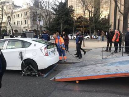 Tow trucks are taking away parked taxicabs.