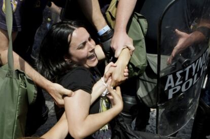 Agentes antidisturbios detienen a una participante en las manifestaciones convocadas ante el Parlamento griego para protestar contra los recortes del gasto público.