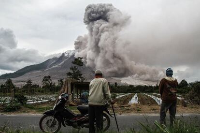 Dos lugareños indonesos observan la erupción del volcán Mount Sinabung en Karo, Sumatra (Indonesia).