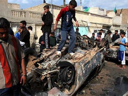 Varios niños juegan alrededor de los restos de un coche calcinado por un mortero en Baghdad.