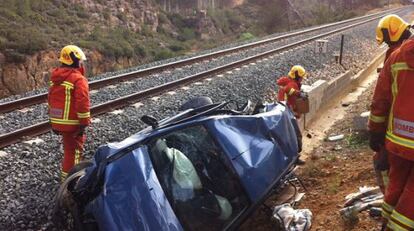 Bomberos junto al veh&iacute;culo arrollado por un tren en Siete Aguas, en una imagen facilitada por el Consorcio Provincial de Valencia.