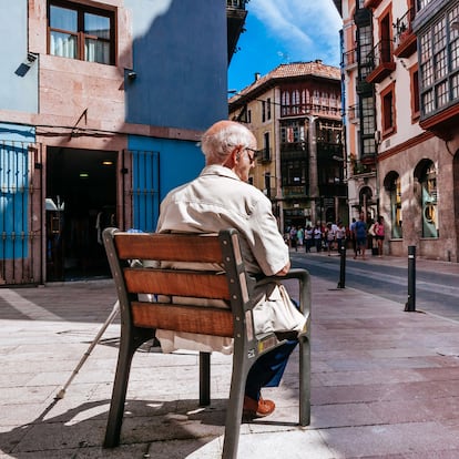 LLANES, ASTURIAS, SPAIN - 2015/07/07: Senior man sitting on a public bench and people walking down a pedestrian shopping area among traditional houses. (Photo by Raquel Maria Carbonell Pagola/LightRocket vía Getty Images)
