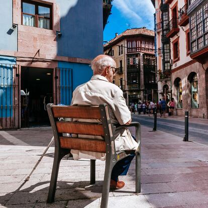 LLANES, ASTURIAS, SPAIN - 2015/07/07: Senior man sitting on a public bench and people walking down a pedestrian shopping area among traditional houses. (Photo by Raquel Maria Carbonell Pagola/LightRocket vía Getty Images)