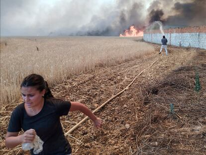 Una joven huía de las llamas mientras un vecino intentaba proteger su casa del incendio de Tábara (Zamora), el lunes.