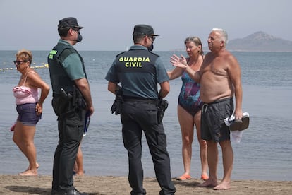 Varios bañistas muestran su enfado por el estado de la laguna a dos agentes de la Guardia Civil. 