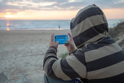 Un menor juega con su móvil a la aplicación “Narcos del Estrecho” en una de las playa de Cádiz.