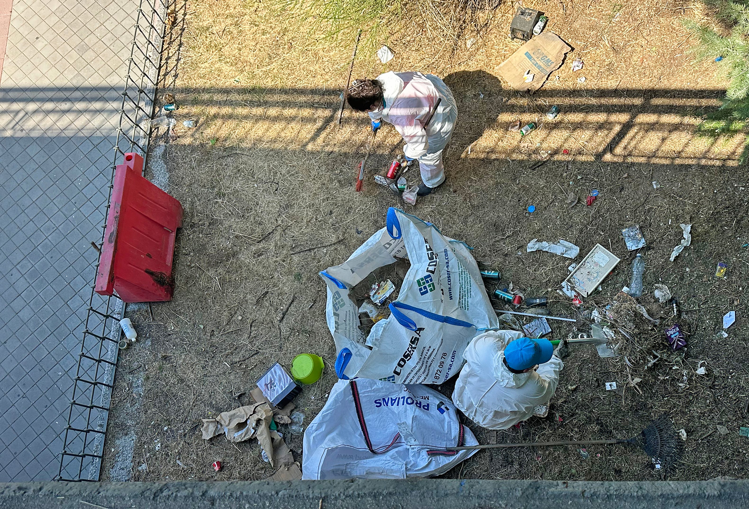 Two workers drag belongings with rakes.