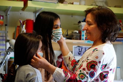 Una mujer prueba a dos niñas una mascarillas realizadas con un tamaño más pequeño (Córdoba).