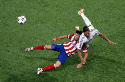 Rafael Varane, del Real Madrid y David Villa chocan al disputar por un balón.