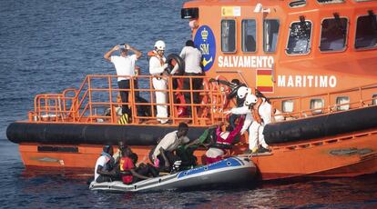 Trabajadores de Salvamento Marítimo ayudan a embarcar a 11 migrantes que cruzaban en un bote de plástico a remos el Estrecho.