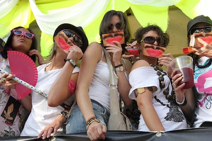 Un grupo de mujeres se ponen imágenes de bocas pintadas de carmín con bigote durante la cabalgata.