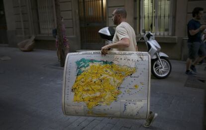 Un hombre, con un mapa de Espa&ntilde;a en el centro de Barcelona.