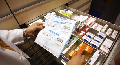 Una farmaceutica buscando un medicamento con la receta en un farmacia de Madrid.