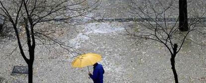 Un hombre se protege de la lluvia en una calle de Madrid.