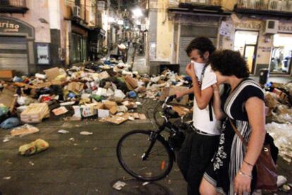 Una pareja camina entre cúmulos de basura en la céntrica calle Toledo de Nápoles.