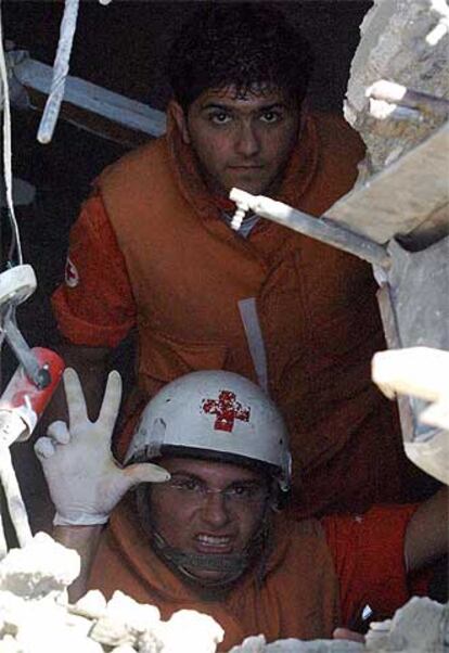 Un miembro  de la Cruz Roja indica la localización de tres cuerpos en un edificio bombardeado en Ghaziye.
