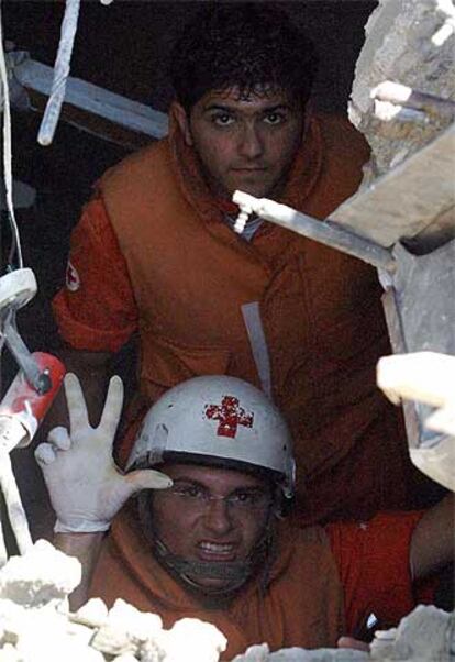 Un miembro de la Cruz Roja indica la localización de tres cuerpos en un edificio bombardeado en Ghaziye.