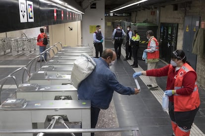 Voluntarios de Protección Civil y de Cruz Roja, en el Metro de Barcelona, donde reparten desde primera hora de la mañana en los transportes públicos de las principales ciudades catalanas mascarillas a los usuarios para tratar de evitar nuevos contagios de coronavirus.