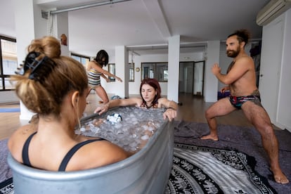 Dos participantes del curso introductorio al método Wim Hof realizan la inmersión en hielo, mientras otros dos entran en calor tras su baño en Yoga Parvati Málaga, el 6 de diciembre de 2022. 